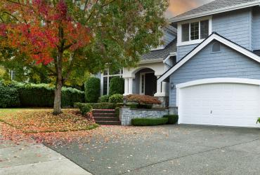 Early autumn residential single family home with colorful tree and sky